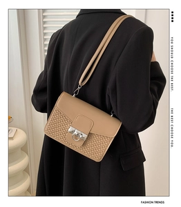 Detail of khaki crossbody bag featuring woven texture and round metal rivet buckle