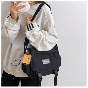 Détail d'un sac messager en nylon noir avec boucles et un porte-clés en peluche mignon