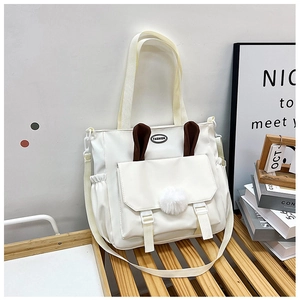 Dettaglio borsa a tracolla in nylon bianco con orecchie di coniglio e pompon decorativi
