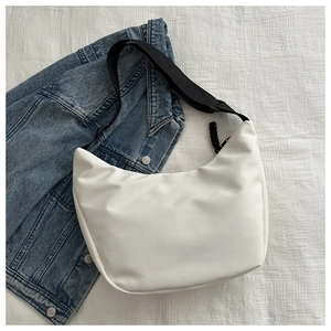 Detail of white nylon hobo bag with adjustable strap and textured zipper pull on denim