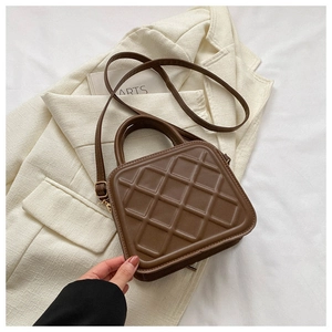 Close-up of brown quilted square bag with textured handle and leather crossbody strap