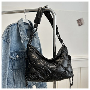 Detail of glossy black quilted puffer bag with fashion logo and woven drawstring cords
