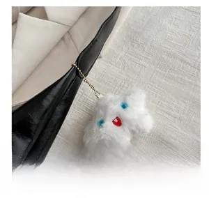 Cute white star-shaped plush pendant with facial features on a black leather bag