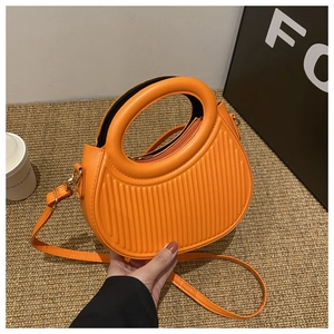 Detailansicht der leuchtend orangen halbkreisförmigen Ledertasche mit Streifen und Goldbeschlag