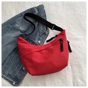 Detail of red crescent crossbody bag with black cord zipper puller and adjustable strap