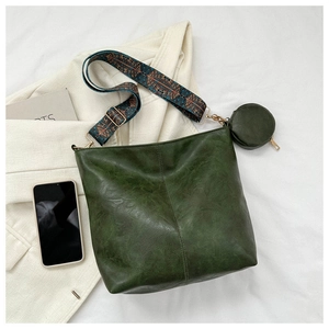 Detail view of dark green leather bucket bag with ethnic jacquard strap and round pouch