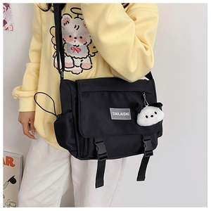 Détail du sac messager en nylon noir avec boucles et porte-clés panda en peluche