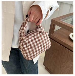 Dettaglio di una borsa a mano quadrata a quadretti bianchi e marroni con manico