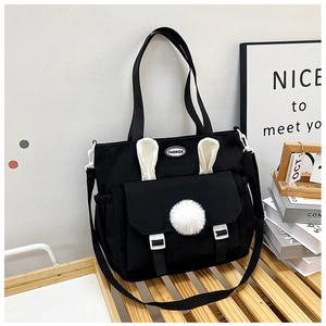 Dettaglio della borsa in nylon nero con graziose orecchie di coniglio e pompon bianchi