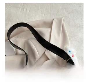 Detail of black leather shoulder bag handle with cute white plush bear charm