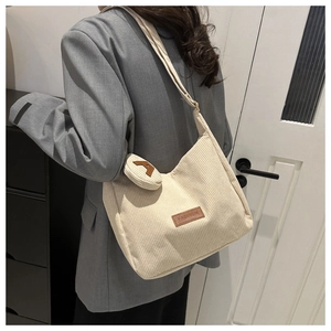 Detail of off-white corduroy hobo bag with mini round coin purse and fashion patch label