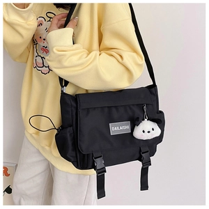 Détail du sac messager en nylon noir avec fermoirs à boucle et pendentif chien en peluche