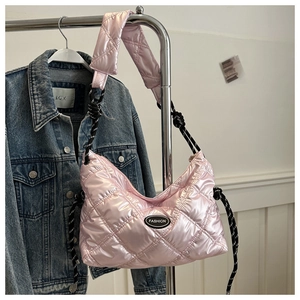 Detail of pink quilted puffer bag with woven rope strap and fashion logo badge
