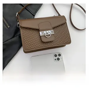 Detail of dark brown square bag with wave embossed texture and silver metal buckle