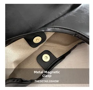 Detail shot of the secure gold magnetic snap closure on a black vintage texture tote bag