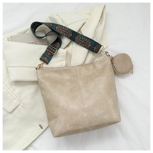 Detail of beige textured tote bag featuring a colorful bohemian wide woven shoulder strap