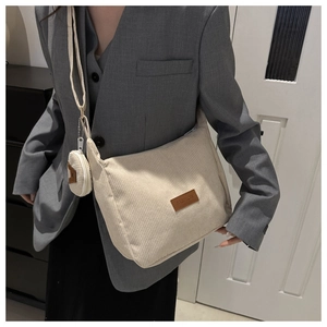 Detail view of ivory corduroy crossbody bag with coin purse on grey blazer outfit