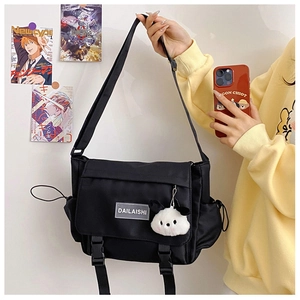 Détail du sac messager en nylon noir avec fermoirs et porte-clés panda en peluche