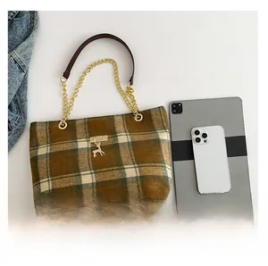 Detail van geruite draagtas met vergelijking van tabletformaat en gouden hardware
