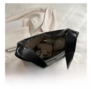 Spacious interior of black leather tote bag showing phones, wallet, and umbrella