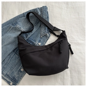 Detail of black nylon dumpling bag with textured zipper pull and wide shoulder strap