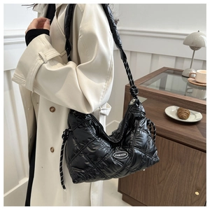 Detail of black glossy quilted shoulder bag with woven rope strap and fashion logo