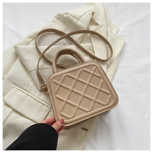 Detail of beige quilted faux leather bag with gold hardware and top handle strap