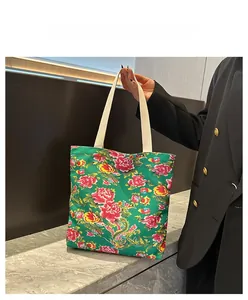 Detail of green floral canvas tote bag featuring traditional Chinese red peony pattern
