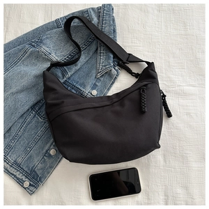 Detail view of black crescent dumpling bag with woven zipper pull and adjustable strap