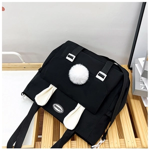 Dettaglio borsa a tracolla in nylon nero con orecchie di coniglio bianche e pompon