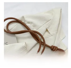 Detail of a brown leather tote bag showing the stylish knotted handle and metal ring