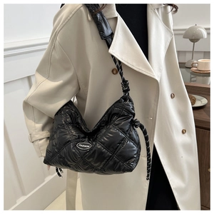 Detail of black quilted padded bag with braided rope strap and fashion leather patch