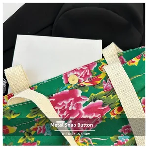 Detail of the golden magnetic metal buckle closure on the green floral canvas tote bag
