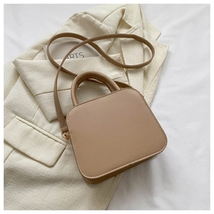 Close-up of light khaki quilted crossbody bag with top handle and golden hardware