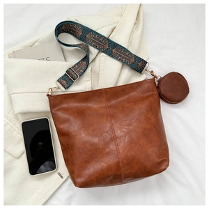 Brown leather hobo bag with a wide embroidered geometric shoulder strap and coin purse