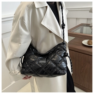 Detail of black quilted puffer bag featuring a glossy finish and fashion logo plaque
