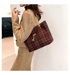Detail van rood-groene geruite shopper met gouden ketting en hertenbedeltje op een model