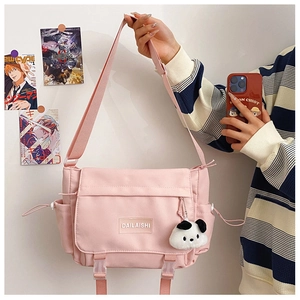 Détail d'un sac messager rose avec pendentif panda et poche latérale à cordon serré