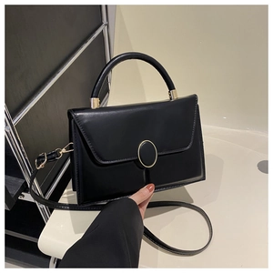 Close-up of black matte leather handbag featuring gold ring buckle and stitch detail