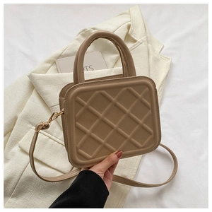 Detail showing brown quilted crossbody bag with top handles and faux leather texture