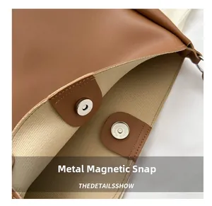 Detail view of the secure magnetic silver buckle closure on a brown leather tote bag