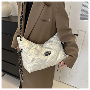 Detail view of silver quilted nylon crossbody bag with black and white woven rope strap