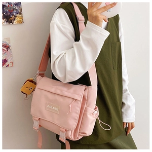 Vue détaillée du sac messager rose en toile avec pendentif ours et sangle réglable large