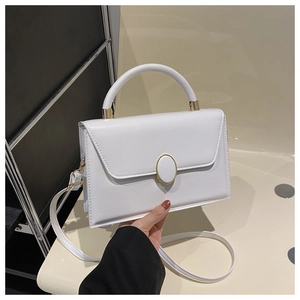 Close-up of white leather square handbag featuring golden oval buckle and fine stitching