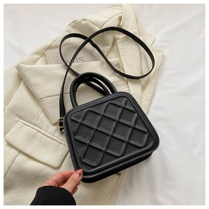 Detail view of black quilted faux leather handbag with gold hardware and top handle