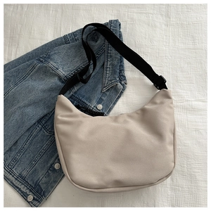 Detail showing beige nylon crescent bag with adjustable black shoulder strap and zipper