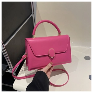 Detail of fuchsia square handbag showing the golden twist lock and smooth leather texture