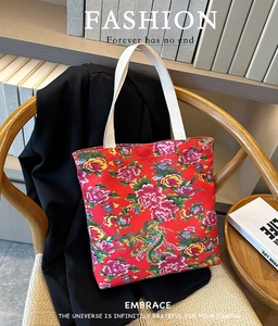 Detailed close-up of a red floral tote bag with peony patterns on a woven chair