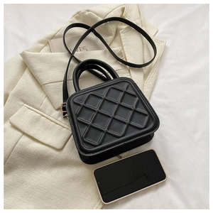 Detail shot of black quilted crossbody bag with top handle and adjustable shoulder strap
