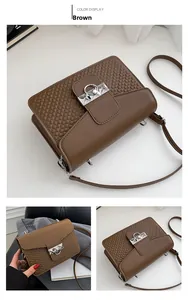 Detail view of brown textured synthetic leather crossbody bag with silver buckle and strap